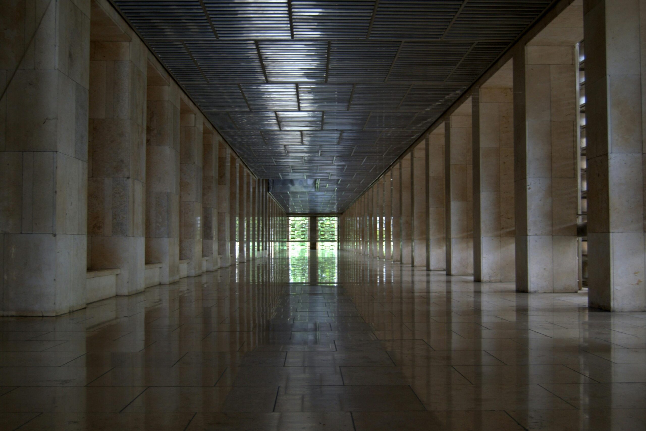 A stunning symmetrical stone corridor with geometric lines and reflections in Jakarta, Indonesia.
